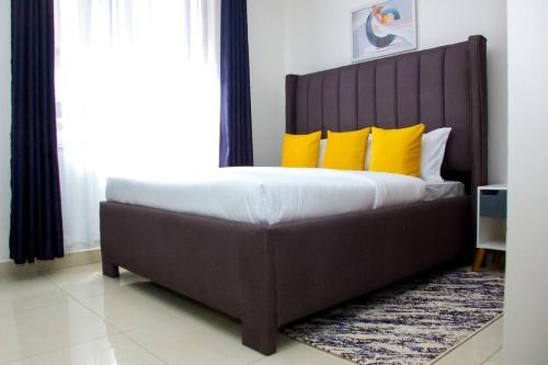 ein Schlafzimmer mit einem großen Bett mit gelben Kissen in der Unterkunft Nala House close to JKIA and SGR in Nairobi