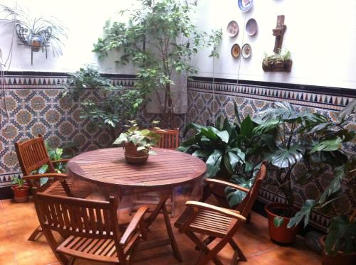 une table et des chaises en bois dans une pièce ornée de plantes dans l'établissement Hostal Senero, à Mérida