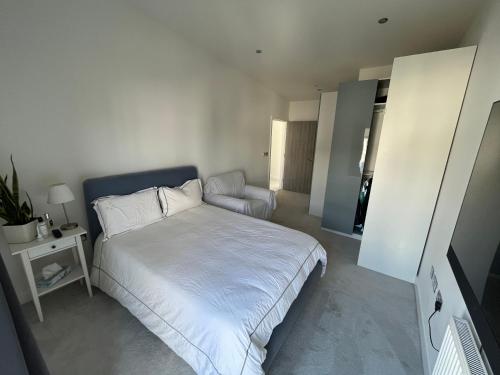 a small bedroom with a white bed and a chair at Sevenoaks Centre Hideaway in Sevenoaks