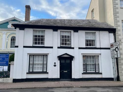 una casa blanca con una puerta negra en una calle en The Hame, en Monmouth