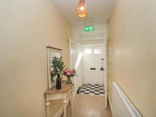 a hallway with a door with a mirror and flowers on a table at The Hame in Monmouth