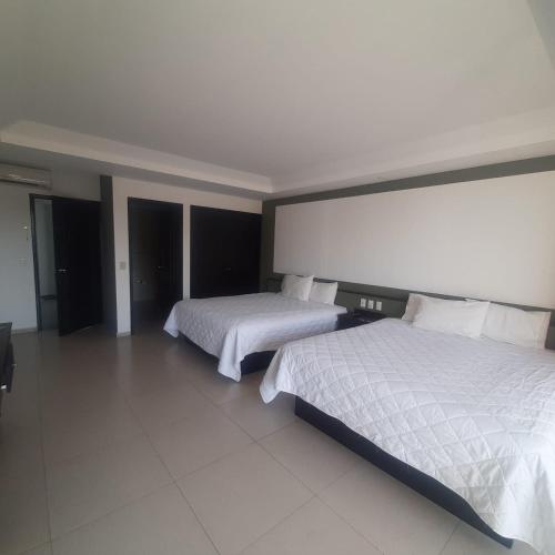 a hotel room with two beds with white sheets at Hotel Borda Cuernavaca in Cuernavaca