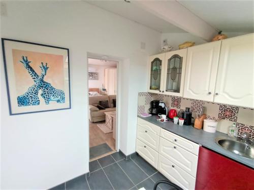 a kitchen with white cabinets and a red refrigerator at Studio Mer & Aa-terrasse-jardin-WIFI-parking-classé 3 étoiles in Grand-Fort-Philippe