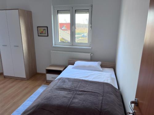 um pequeno quarto com uma cama e uma janela em Apartman Magnolia em Petrovina Turopoljska