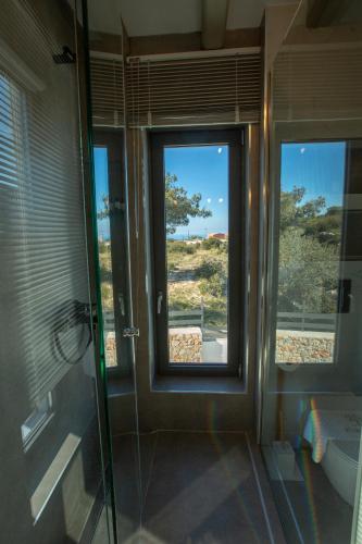 a bathroom with a glass shower and a window at Eliandreia Luxury Villas in Kalamitsi