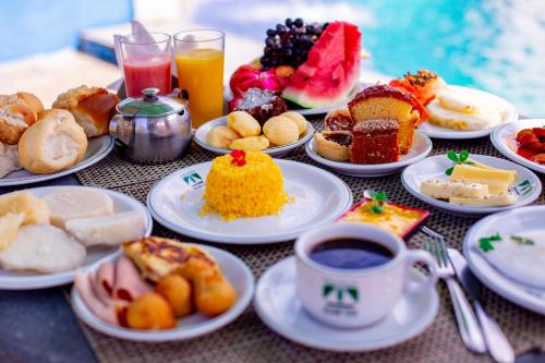 a table with plates of food and a cup of coffee at Hotel Pousada Mahon Mar in Praia do Frances