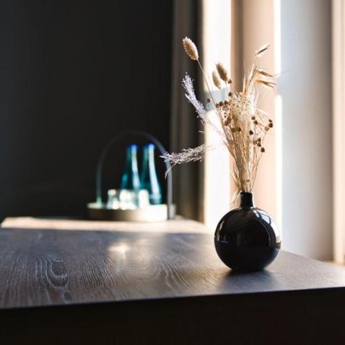 a black vase with flowers in it on a table at Landhaus Gut Halte in Papenburg