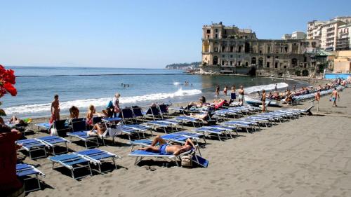 um grupo de pessoas sentadas em cadeiras em uma praia em Suite Riviera 84 em Nápoles