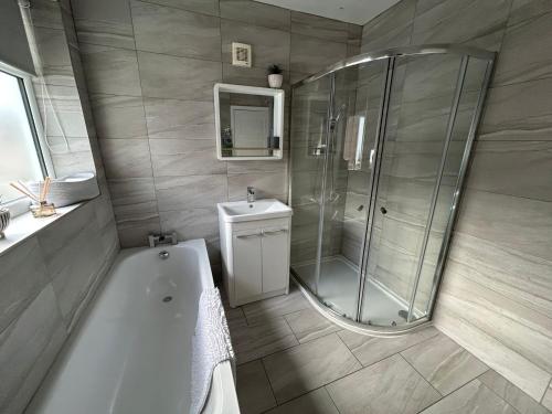 a bathroom with a shower and a tub and a sink at Light And Spacious Highcross Apartment in Poulton le Fylde