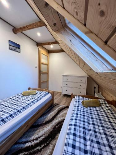 two beds in a room with wooden ceilings at Pokoje gościnne 28 w skosie in Zawadka