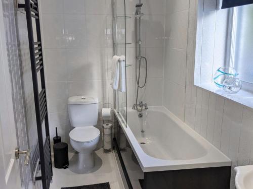 La salle de bains blanche est pourvue de toilettes et d'une baignoire. dans l'établissement Strathclyde Cottage North, à Skelmorlie