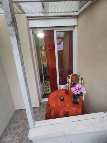 een tafel en een stoel met een vaas met bloemen bij Appartement fonctionnel et équipé en RDC avec petite terrasse couverte au calme in Franqueville-Saint-Pierre