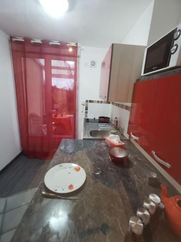 une cuisine avec un comptoir et une porte rouge dans l'établissement Appartement fonctionnel et équipé en RDC avec petite terrasse couverte au calme, à Franqueville-Saint-Pierre