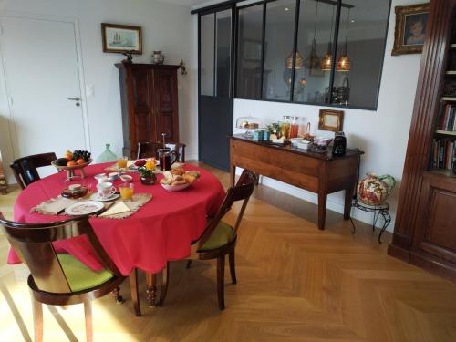 uma sala de jantar com uma mesa vermelha e um piano em Chambre d'hôtes Seiz Breur em Lancieux