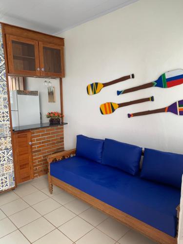uma sala de estar com um sofá azul e pinturas na parede em Chalé beira mar Jacaraipe em Serra