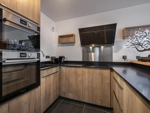 - une cuisine avec des placards en bois et des appareils noirs dans l'établissement Appartement T4 à Courchevel, proche des pistes, avec terrasse, parking, et services inclus - FR-1-563-13, à Courchevel