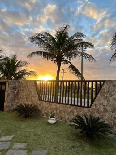eine Terrasse mit einem Zaun und einer Palme in der Unterkunft Casa familiar pé na areia in Cabo Frio