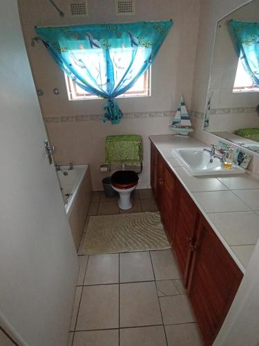 a bathroom with a sink and a toilet and a window at Neptune corner in Hibberdene