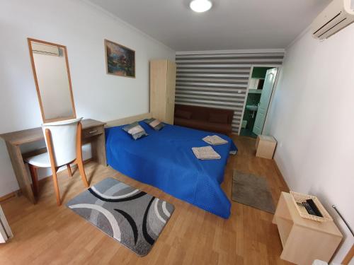 a small bedroom with a blue bed and a desk at Party Vendégház in Hajdúszoboszló