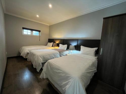 three beds in a room with white sheets at ilanda Guest House in White River