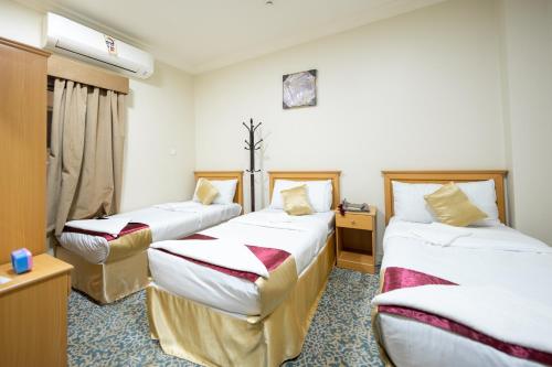 a hotel room with three beds and a window at فندق الفنار العزيزية in Makkah