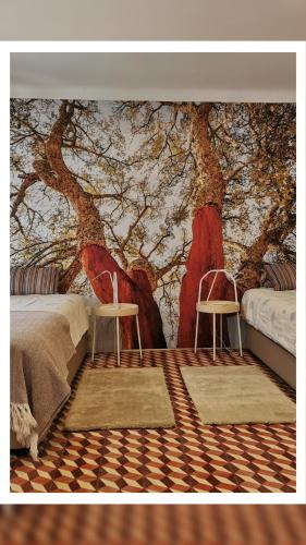 a room with two chairs in front of a tree mural at 4Bs - Birds & Bicycles in Castro Verde