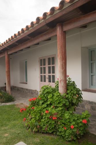 a house with a pillar and flowers in front of it at Tampu in Cachí
