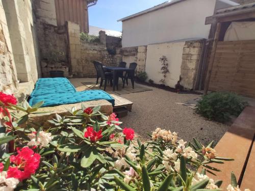 patio z łóżkiem, stołem i kwiatami w obiekcie Gite du four à pain w mieście Benais