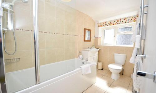 a bathroom with a tub and a toilet and a shower at Sea Nook in Brixham