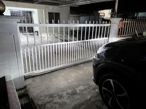 una cerca blanca en un estacionamiento con un coche en Simple Beseri Homestay, en Kangar