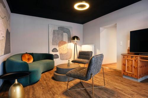 a living room with a couch and two chairs and a television at Das Kronberg Hotel - Adults Only - inkl Soft- und Heißgetränkeflat in Bodenmais