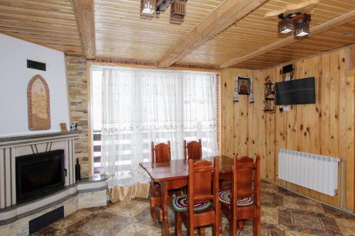 Cottage "Karpatske Shale" في ياريمتشي: غرفة طعام مع طاولة وكراسي وتلفزيون