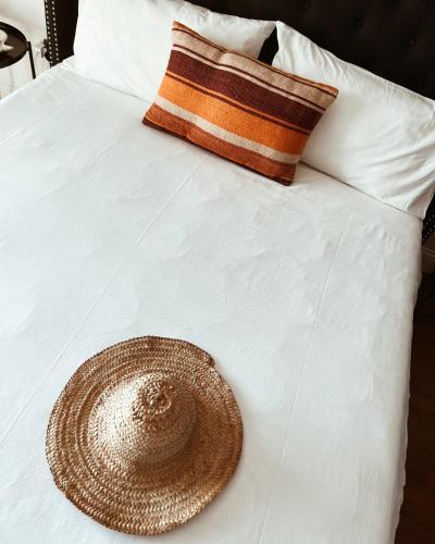 a straw hat sitting on top of a white bed at KeRo Luxury Rooms in Cagliari