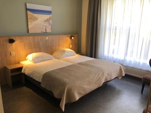 a bedroom with a large bed and a window at Hotel "De Klok" in Buren