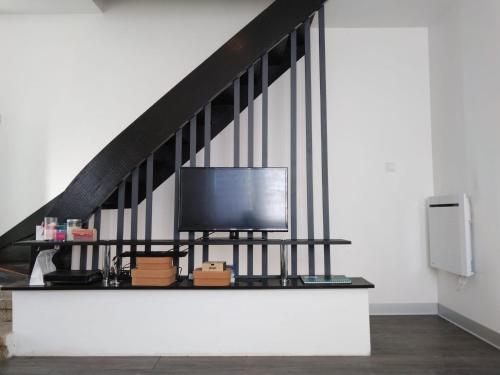 a tv sitting on a table under a staircase at Duplex Tressange in Tressange