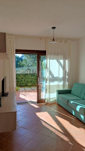 a living room with a green couch and a sliding glass door at sweet home la maddalena in La Maddalena