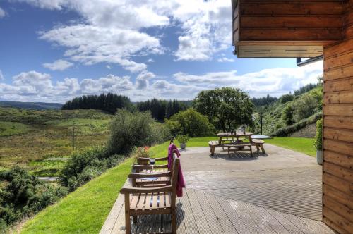 a wooden deck with benches and a picnic table at Aspen Lodge in Oban