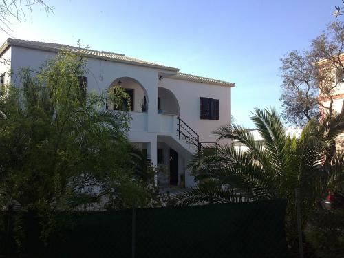 Cette maison blanche dispose d'un balcon et de palmiers. dans l'établissement Alexander Apartments, à Roda
