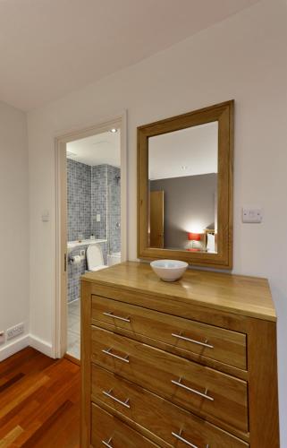 a bathroom with a wooden dresser with a mirror at Farringdon Laceby apartments in London