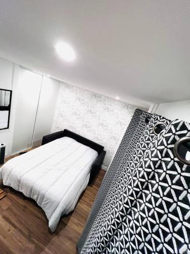 une chambre avec un lit avec une couette noire et blanche dans l'établissement Joli studio une pièce entièrement rénové et équipé classé 2 étoiles, à Balaruc-les-Bains