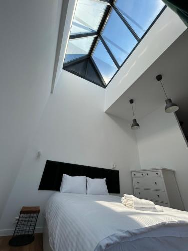 sypialnia z dużym białym łóżkiem i świetlikiem w obiekcie Loft Premium Apartments w Łodzi