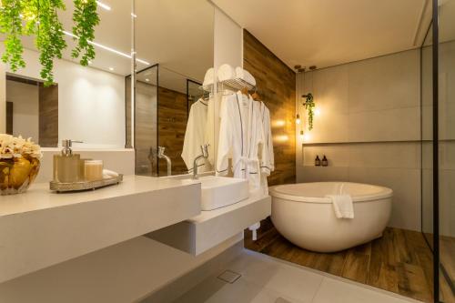 a bathroom with a large white tub and a sink at Natu Hotel Boutique & Spa in Atibaia
