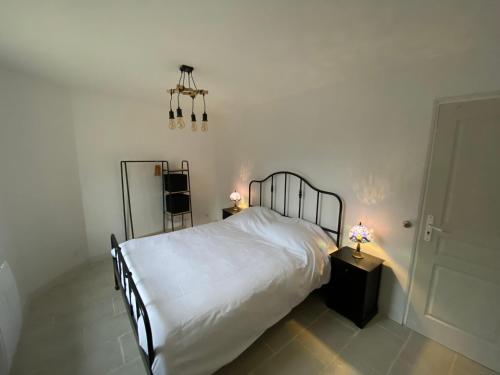 een slaapkamer met een bed met witte lakens en 2 lampen bij Maison - Ancien Chai in Turquant
