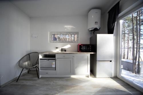 a white kitchen with a refrigerator and a chair at GaujaClub - our BOSE and Bang&Olufsen lofts on a lake in Gauja