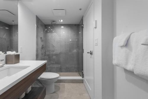 uma casa de banho branca com um chuveiro e um WC. em West Coast Suites at UBC em Vancouver
