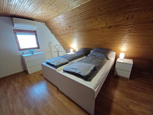 uma cama grande num quarto com uma parede de madeira em Bónom-zugi Pihenőház em Gyomaendrod