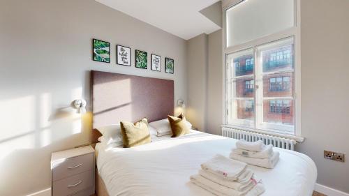 1 dormitorio con 1 cama con sábanas blancas y 2 ventanas en Glassford Residence, en Glasgow