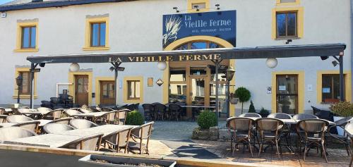 a group of tables and chairs in front of a building at La Vieille Ferme Chassepierre in Chassepierre