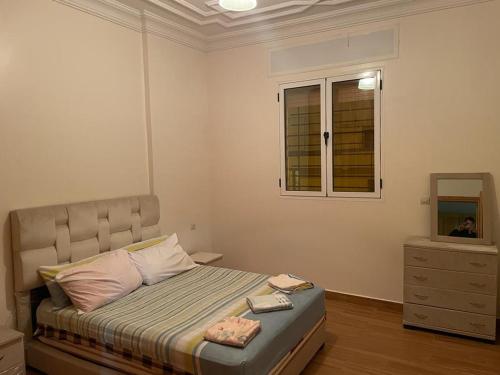 a bedroom with a bed with a window and a dresser at Appartement à louer in Larache