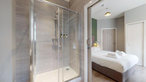 a bathroom with a glass shower and a bed at Glassford Residence in Glasgow